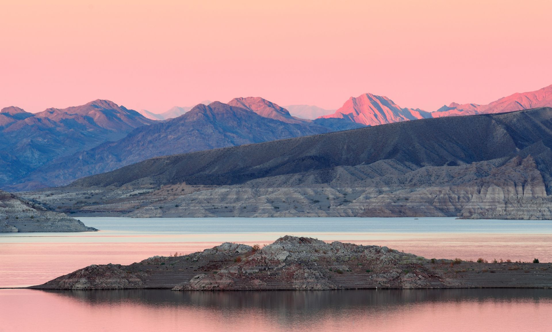A lake with mountains in the background and a small island in the middle.