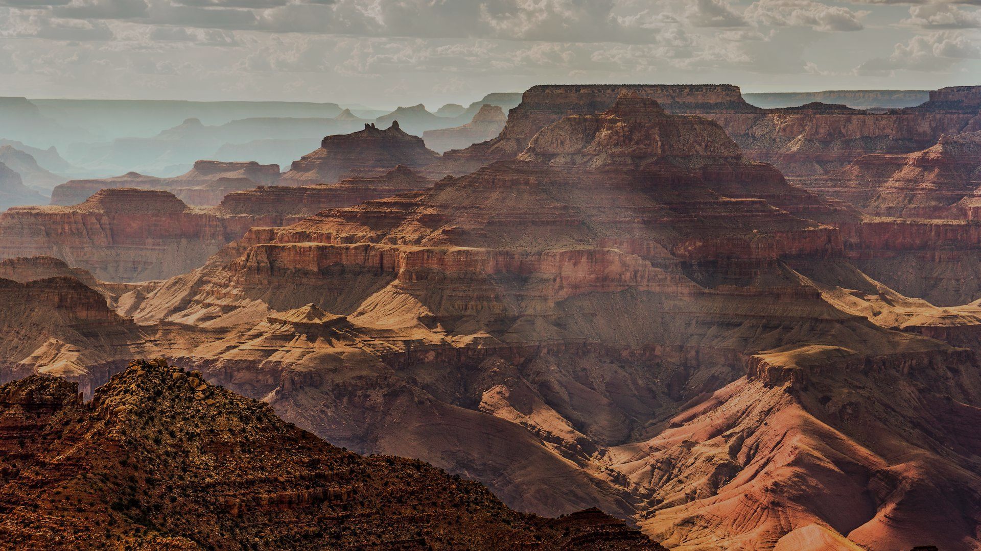The sun is shining through the clouds over the grand canyon.