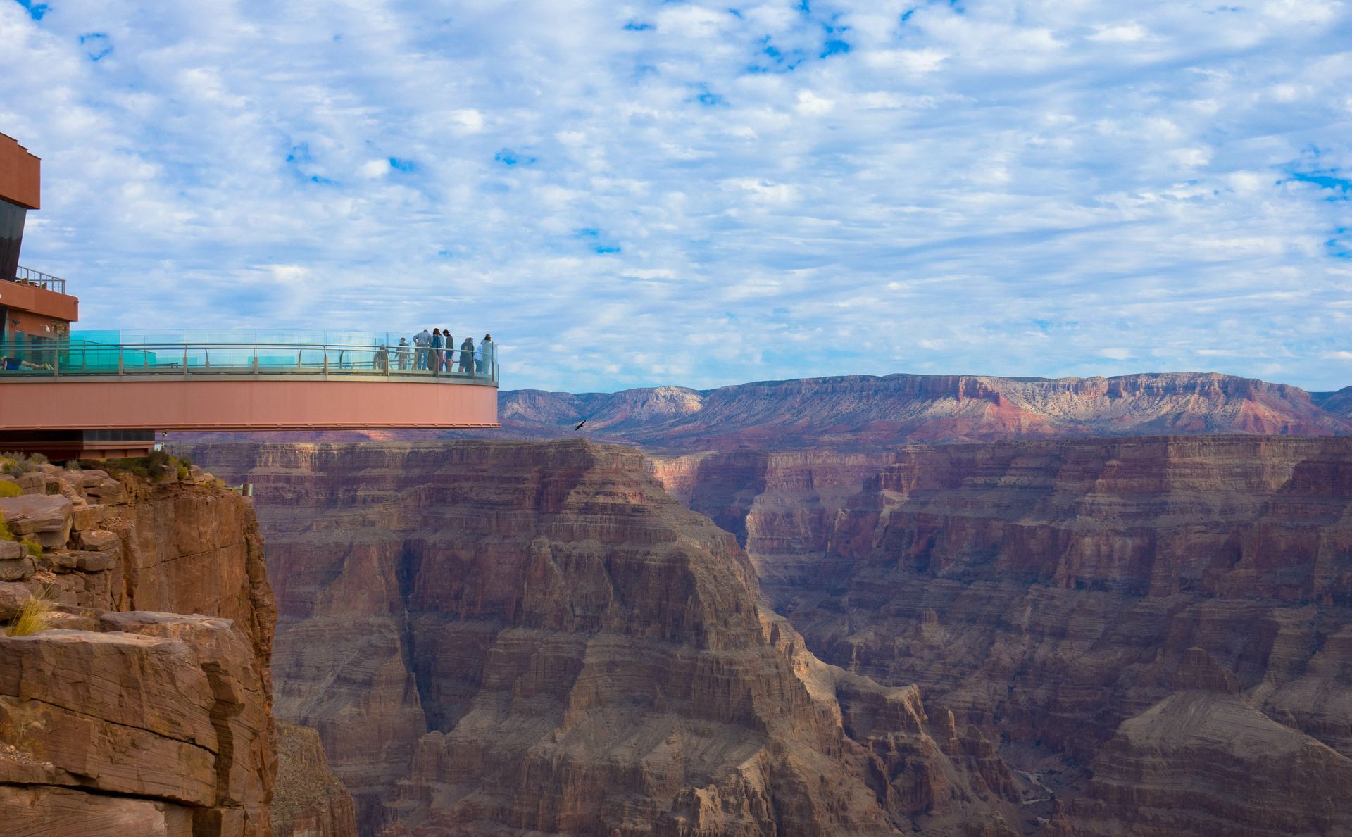 A group of people are standing on top of a cliff overlooking the grand canyon.