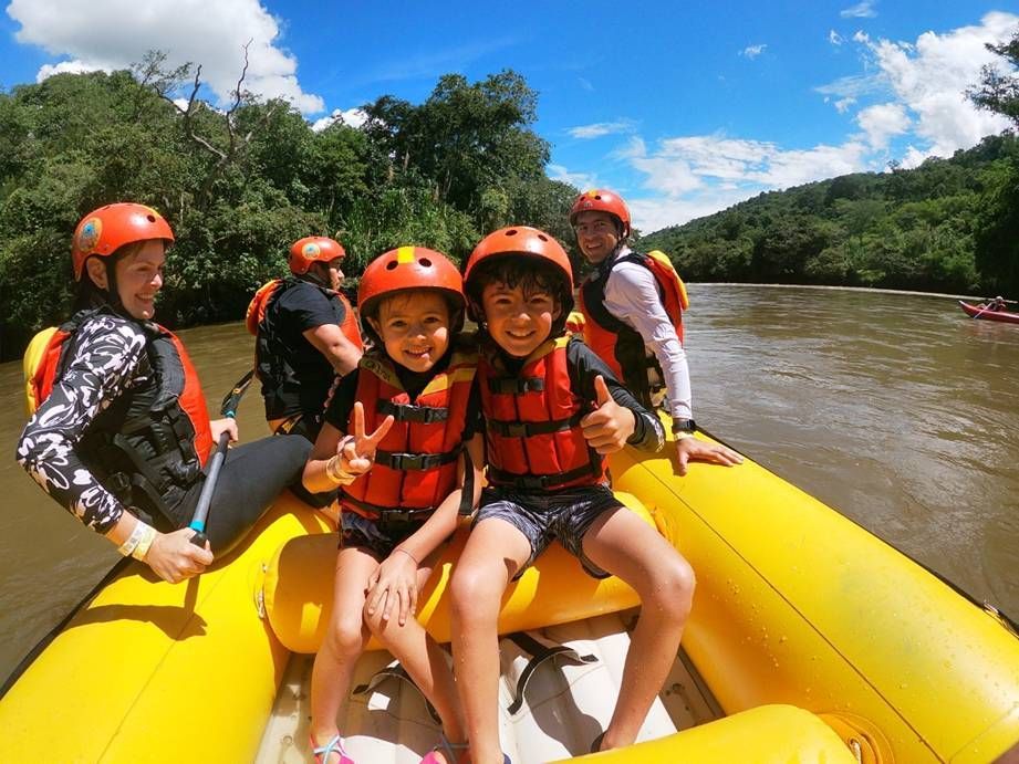 Un equipo de rafting con cascos rojos rema a través de un desfiladero rocoso rodeado de exuberantes acantilados verdes.