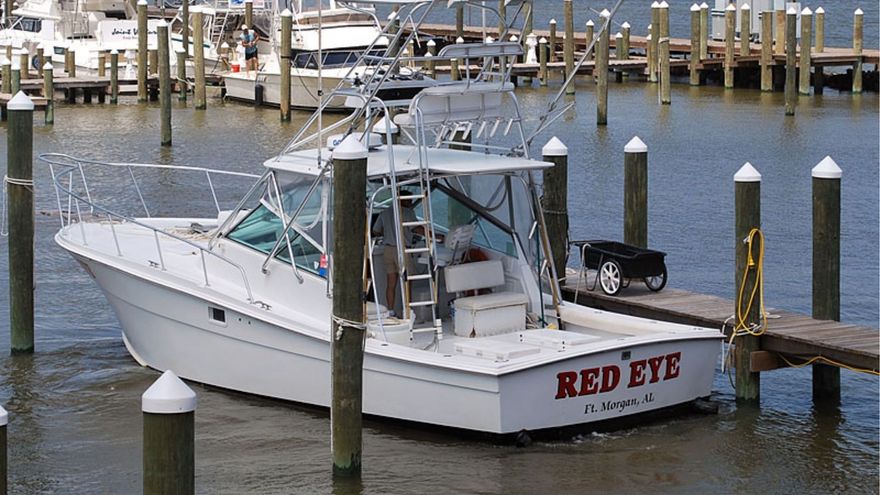 A white fishing boat named "RED EYE" docked at a wooden pier in a marina.