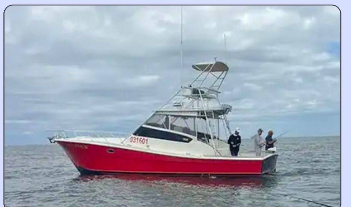 Red-and-white motorboat on choppy water with three people aboard under a cloudy sky