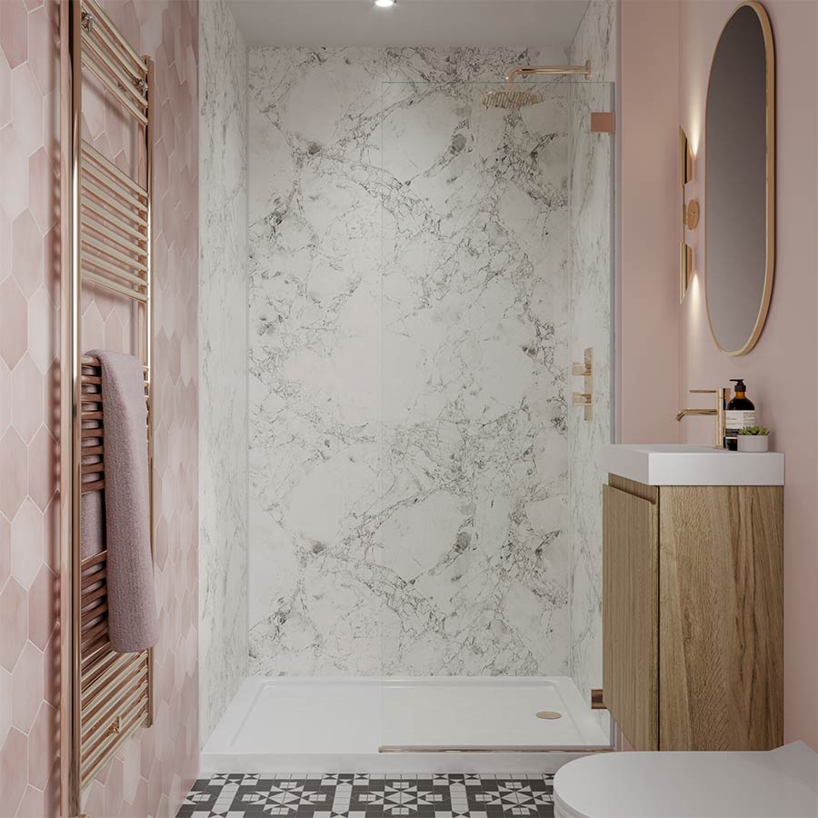 A small bathroom with pink walls, marble shower, wooden vanity, and patterned floor tiles.