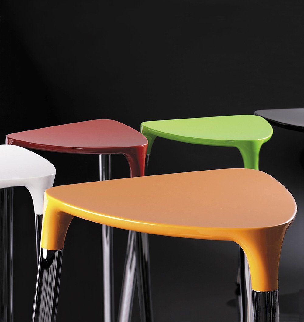 Colorful triangular stools with chrome legs against a dark background.