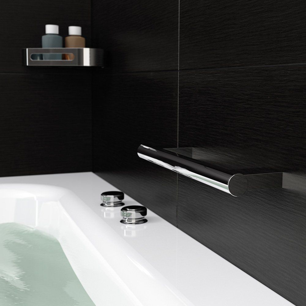 Bathtub corner with chrome accents: handrail, shelf, controls, and black tiled walls.