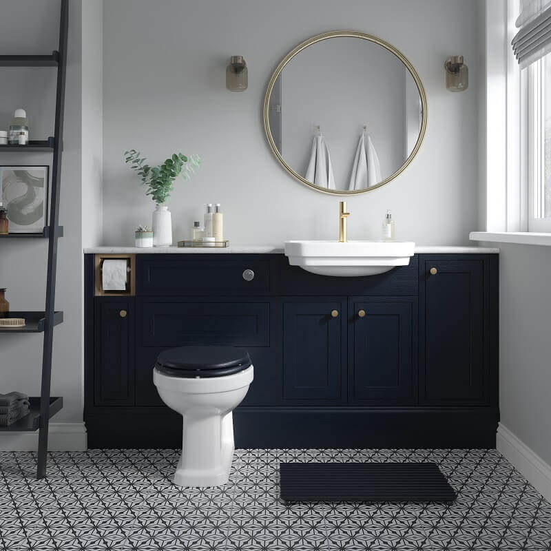 Bathroom with dark blue vanity, white sink, and patterned floor tiles. Gold mirror and fixtures.