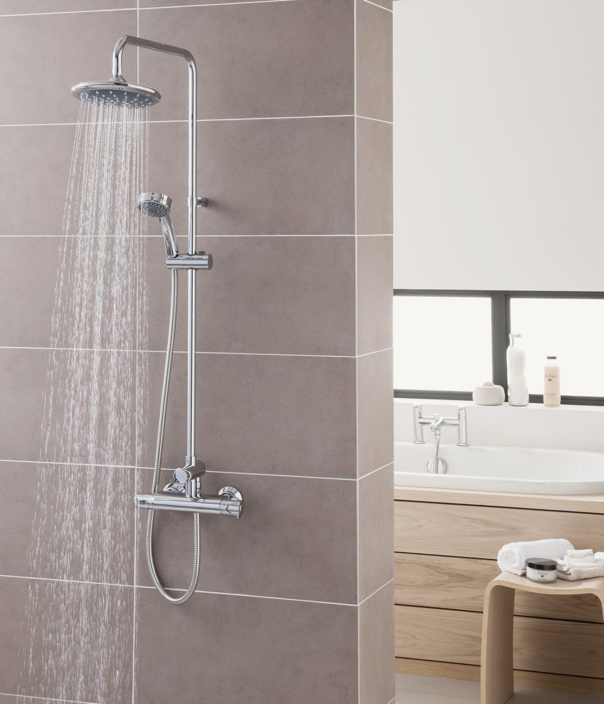 Showerhead with running water, in a modern bathroom with grey tiled wall and wooden accents.