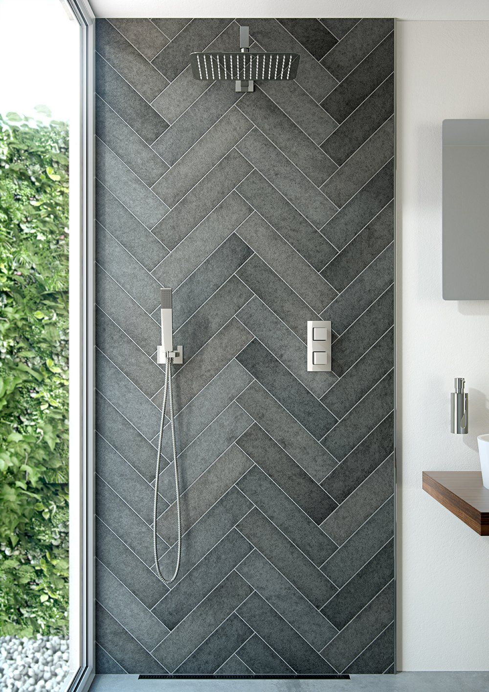 Shower with dark gray herringbone tile wall. Shower head and controls are visible. Next to large window.