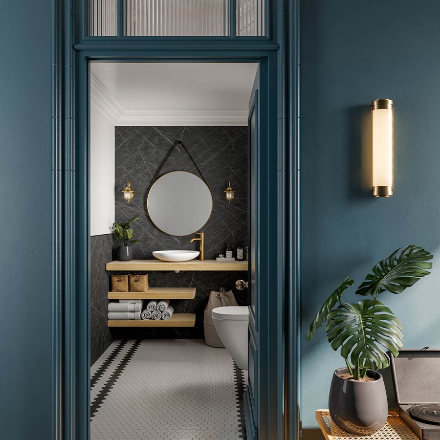 Blue-walled bathroom interior with round mirror, wooden shelves, gold accents, and a potted plant.