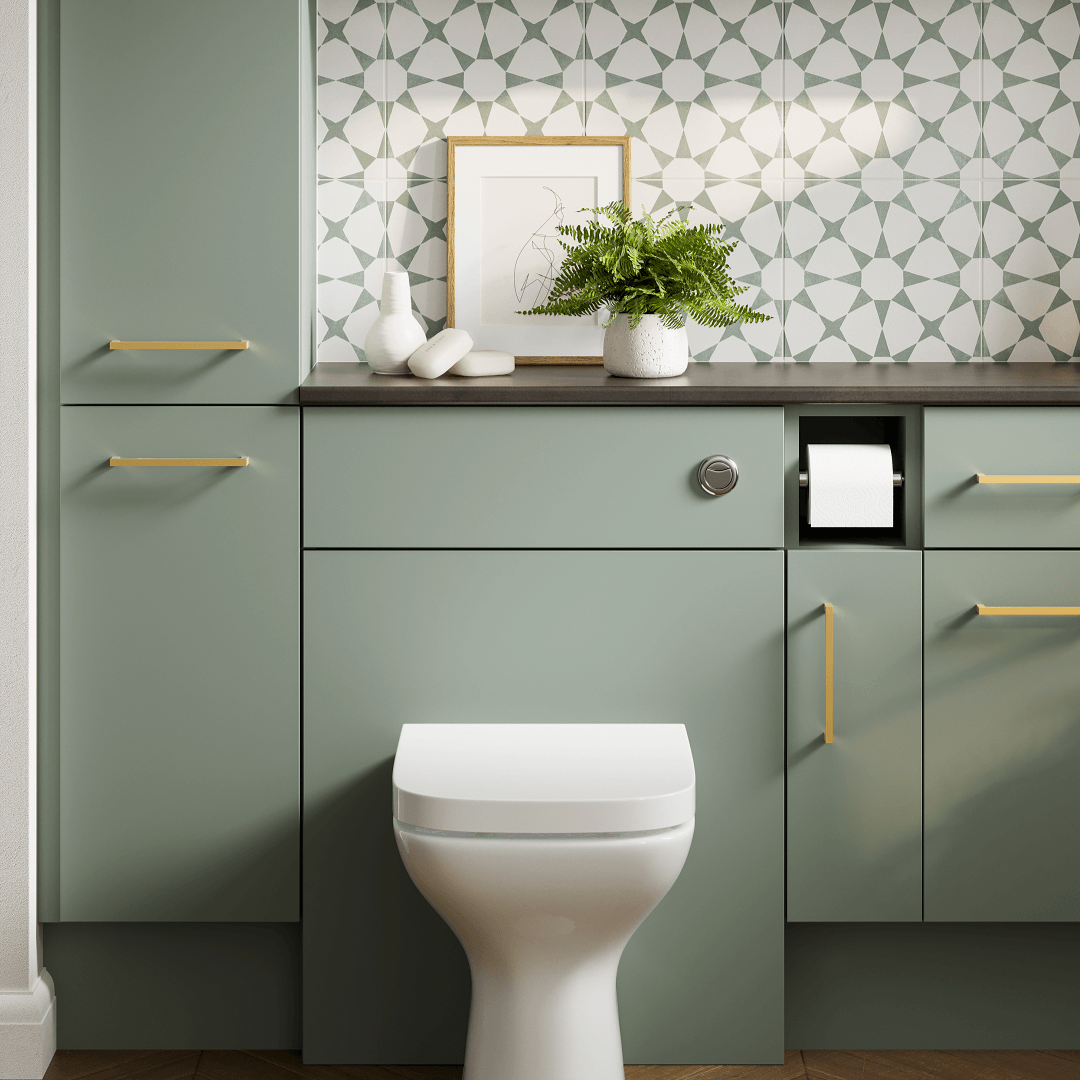 Green bathroom vanity with toilet and built-in toilet paper holder. Decorative patterned tile backsplash and brass hardware.