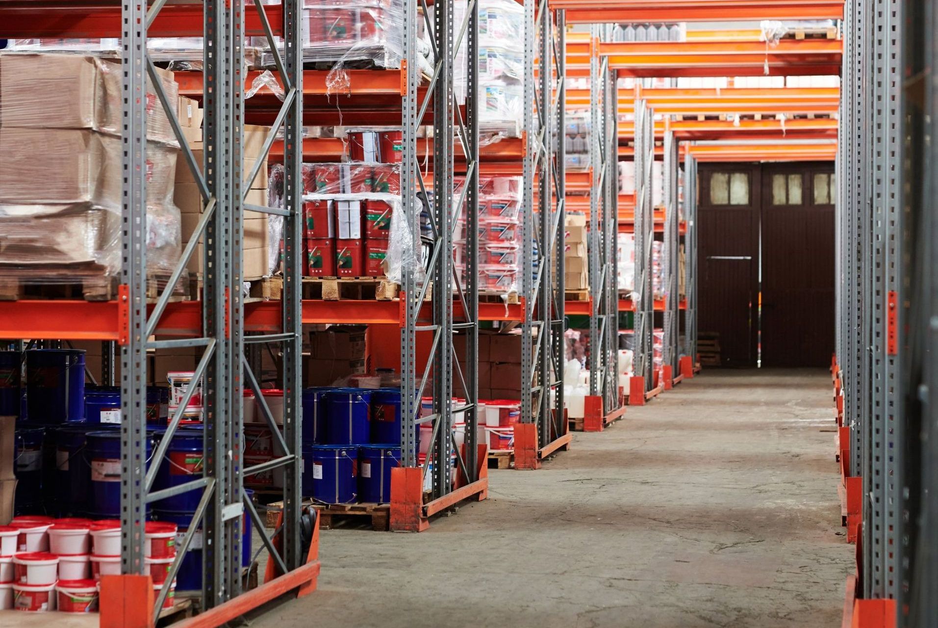 Warehouse aisle with metal shelving loaded with packaged goods.