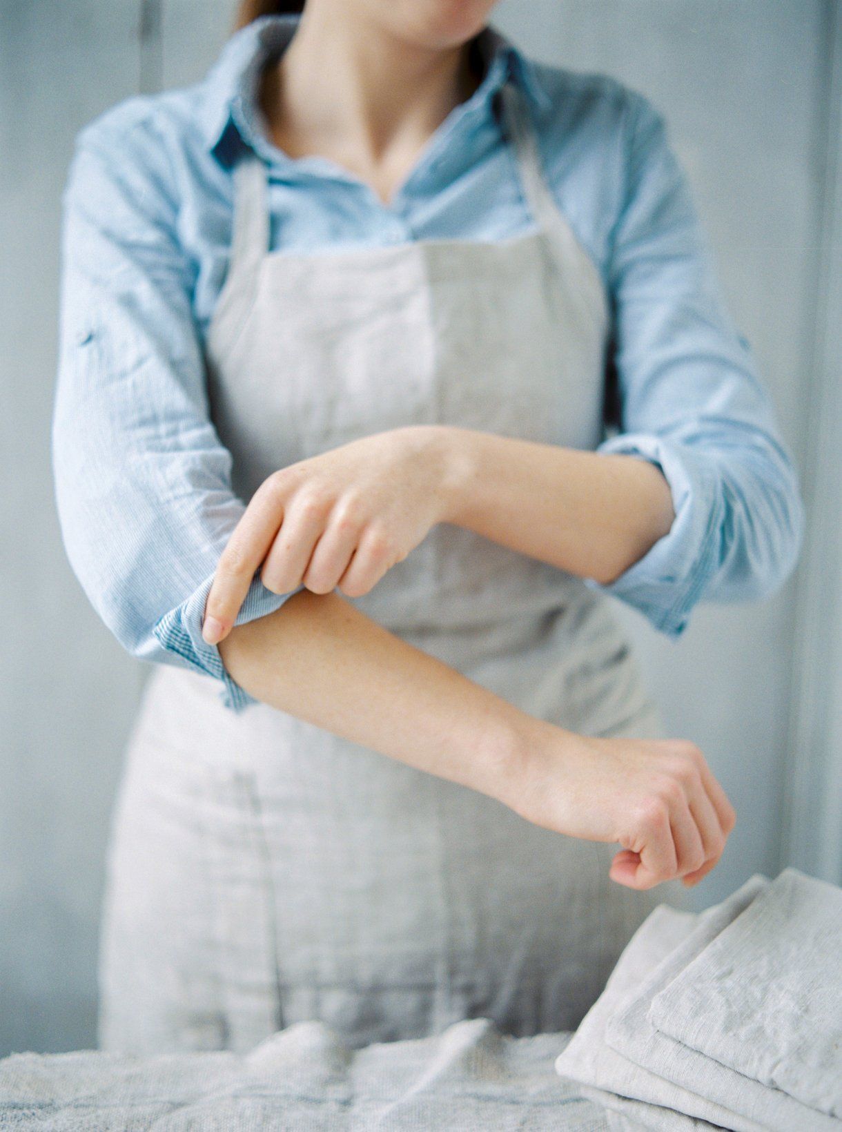 A woman in an apron is holding her elbow.