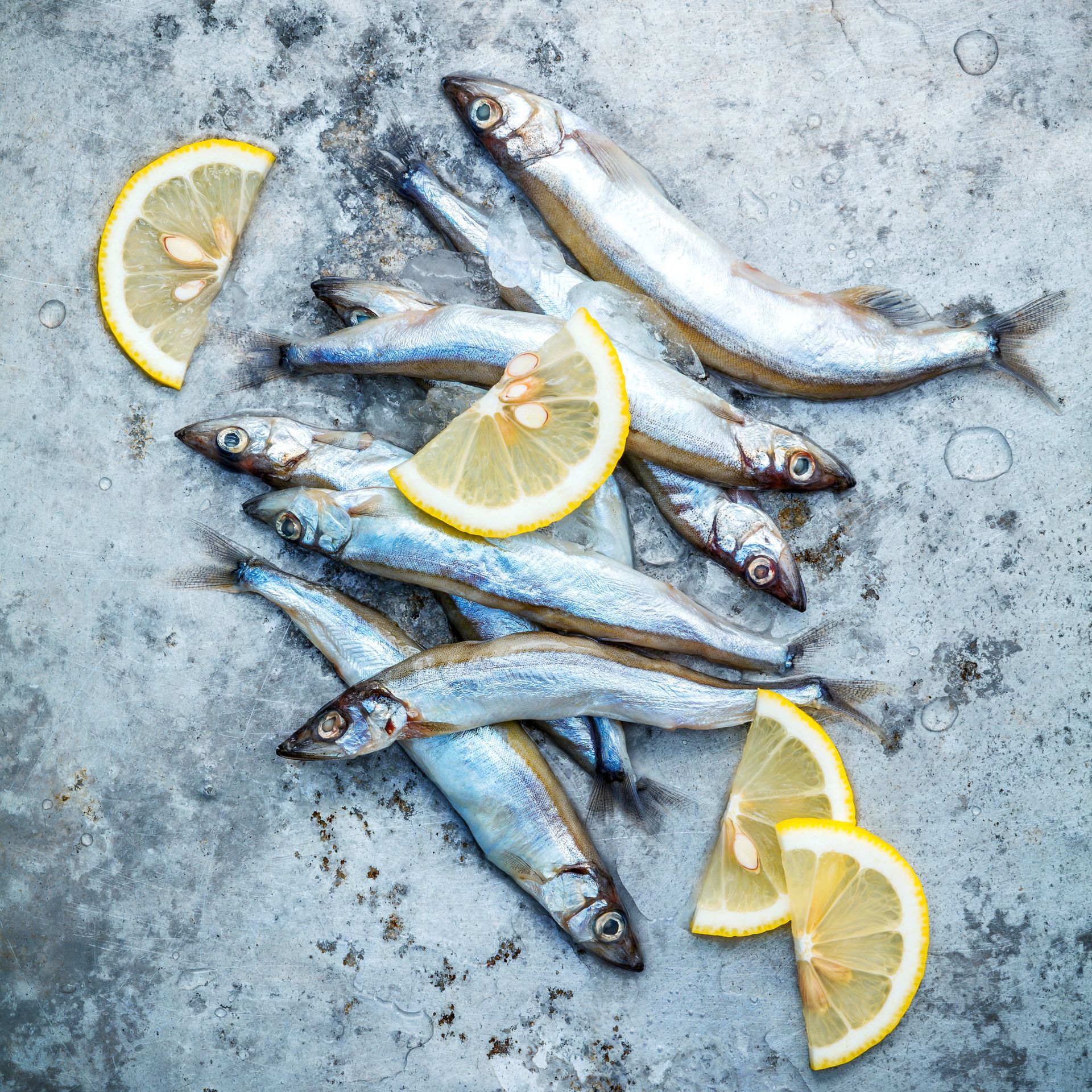 A pile of fish with lemon slices on a table.