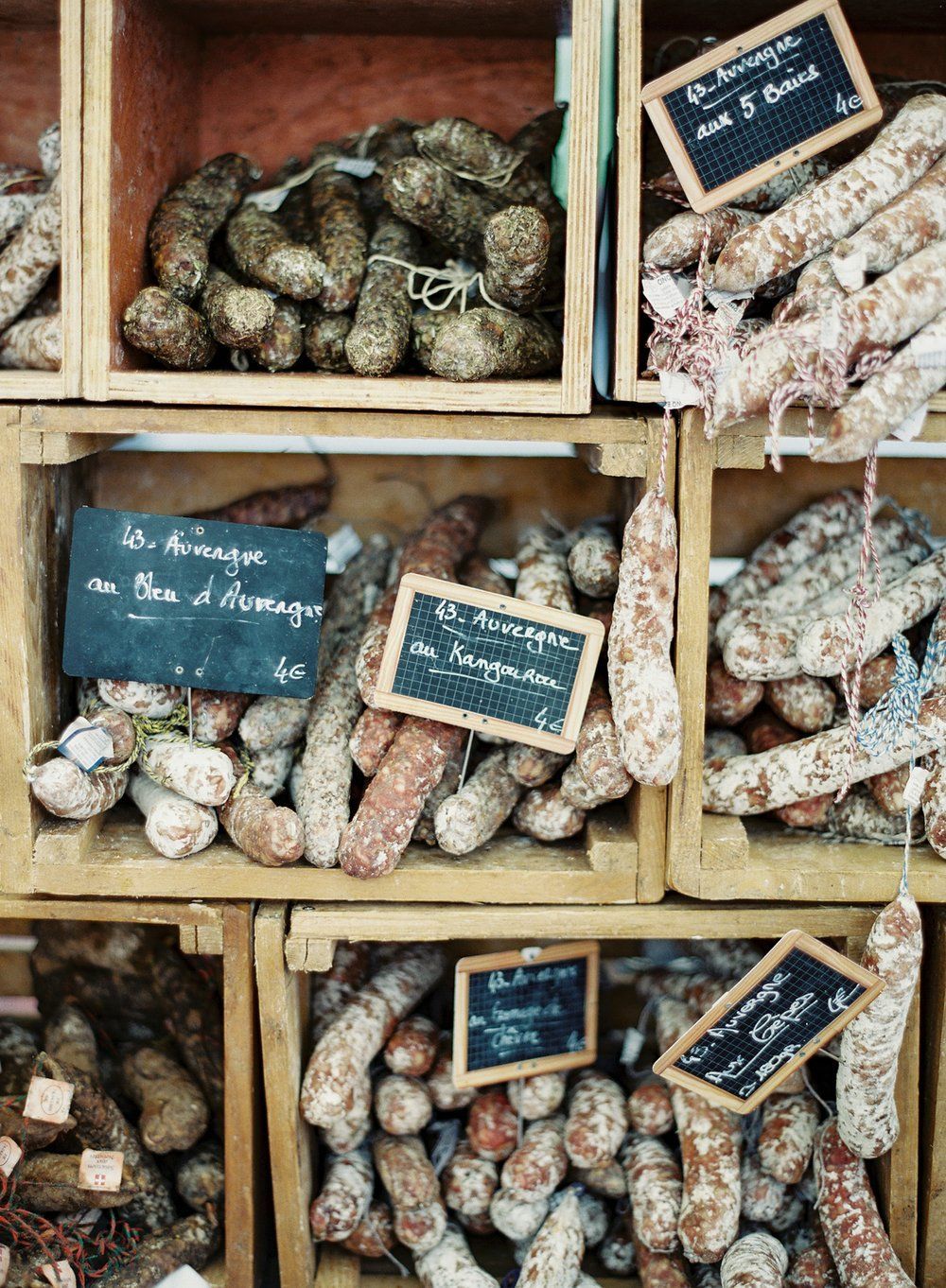 A variety of sausages are displayed in wooden crates.