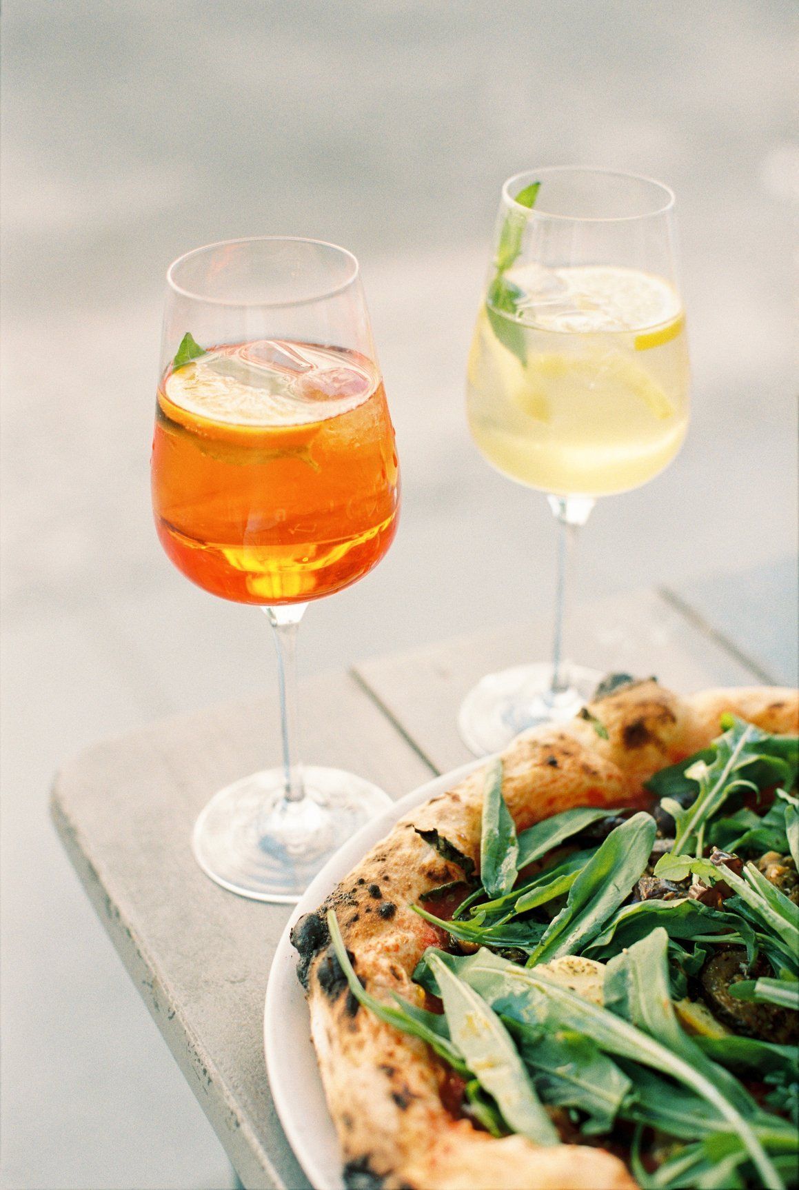 Two glasses of wine and a pizza on a table.