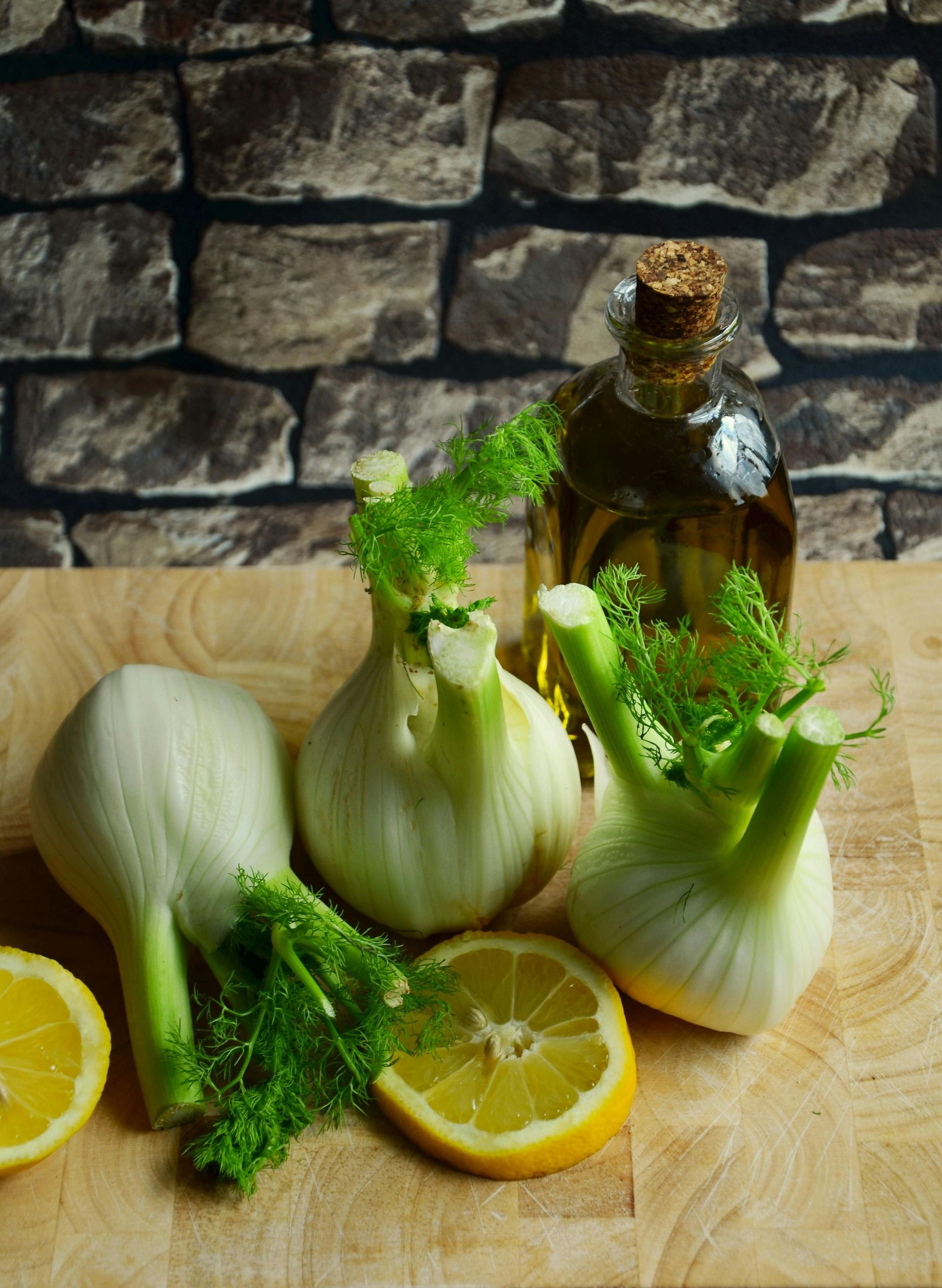 A wooden cutting board topped with vegetables and a bottle of oil.