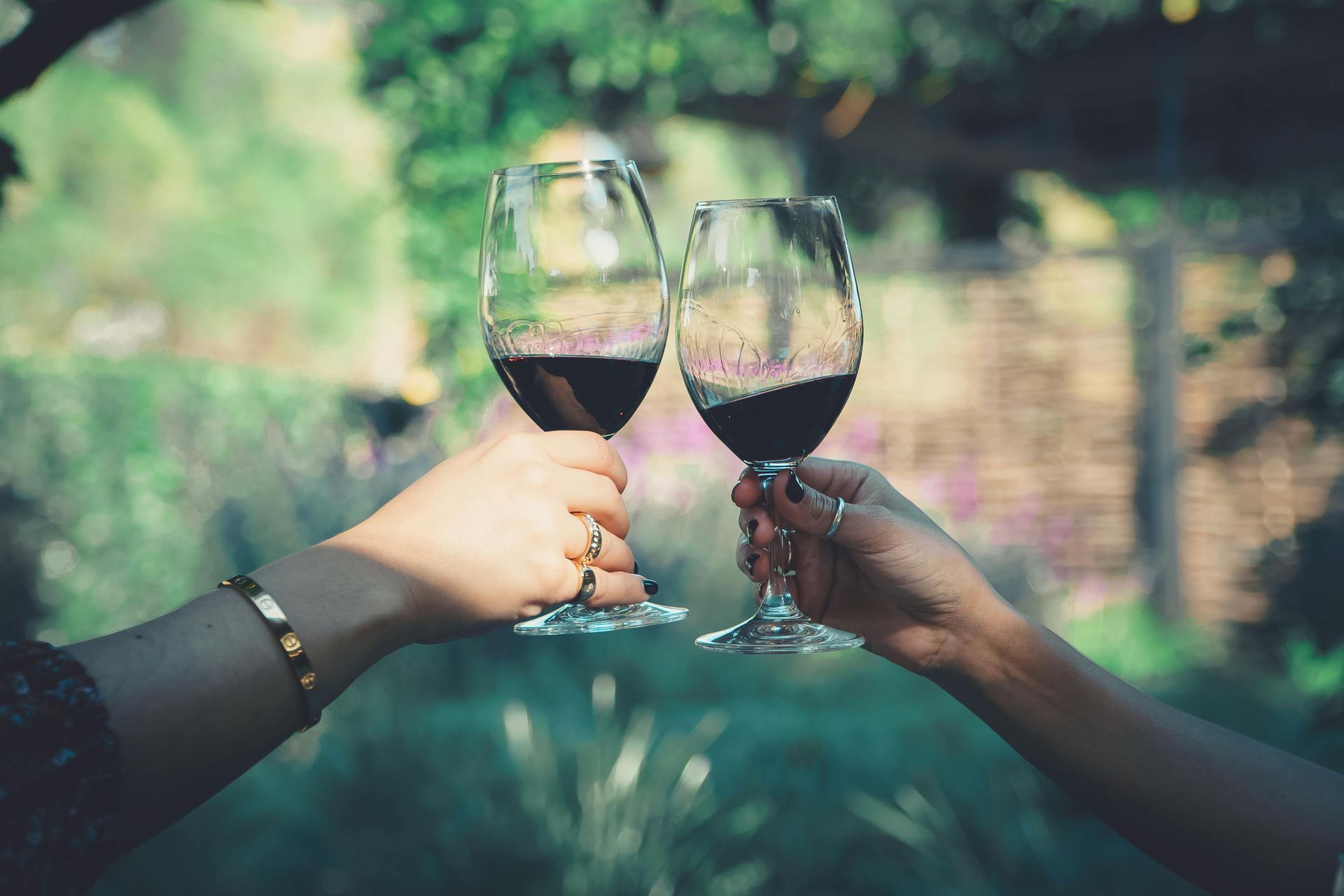 Two people are toasting with wine glasses outside.