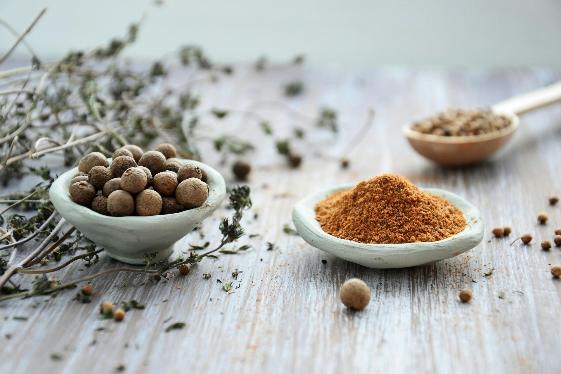 There are two bowls of spices on a wooden table.