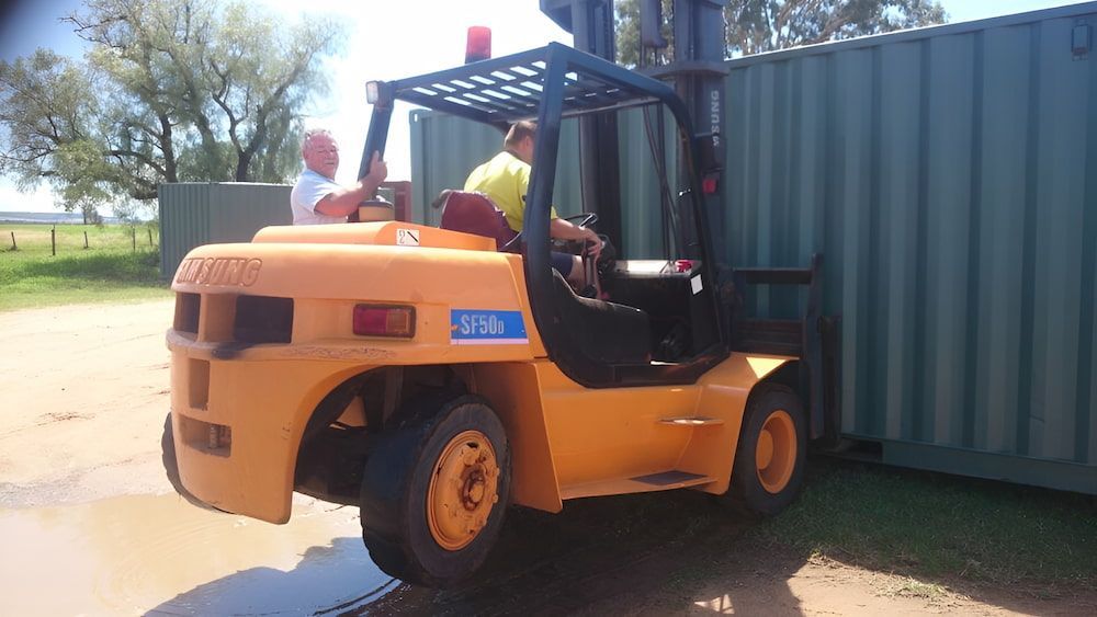 A Yellow Forklift Is Parked In Front Of A Green Container — Ollies Towing & Shipping Container Sales in Kingaroy, QLD