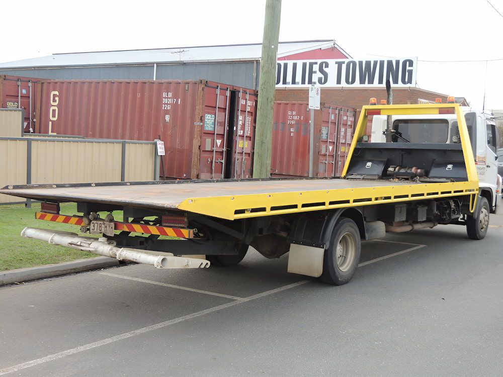 A Yellow Towing Truck Is Parked In Front Of A Building — Ollies Towing & Shipping Container Sales in Kingaroy, QLD