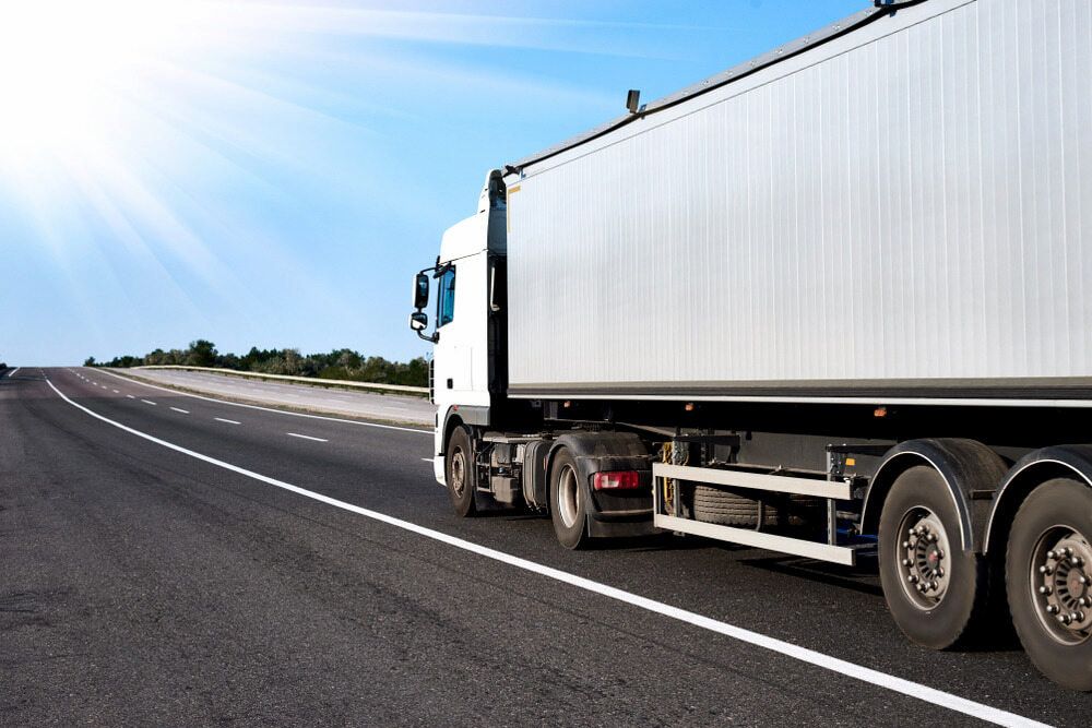 A White Semi Truck Is Driving Down A Highway — Ollies Towing & Shipping Container Sales in Kingaroy, QLD