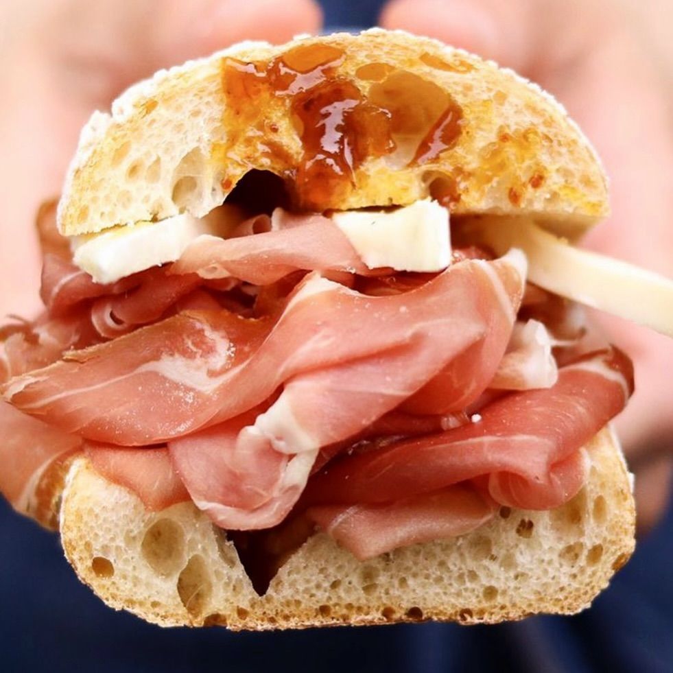 Una persona tiene in mano un panino con un morso staccato