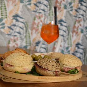 Un tagliere di legno con sopra dei panini e un bicchiere di succo d'arancia.