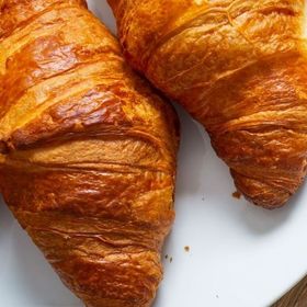 Due croissant sono appoggiati su un piatto bianco.