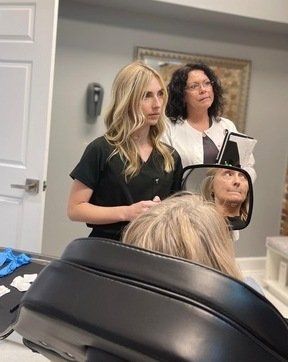 a woman is standing next to a woman in a chair in front of a mirror at ERA Wellness Spa