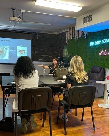 ERA Wellness Spaa group of women are sitting at tables in front of a projector screen at Lush Aesthetics