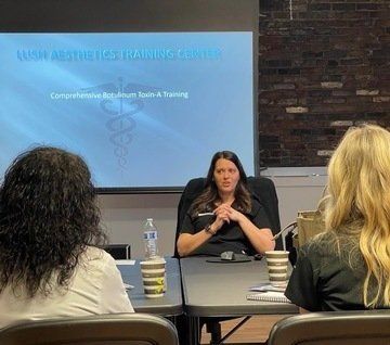 a woman is sitting at a table giving a presentation to a group of people at ERA Wellness Spa