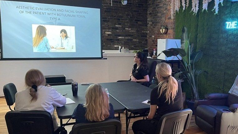 a group of women sit around a table at ERA Wellness Spa injecting the patient with botulinum toxin