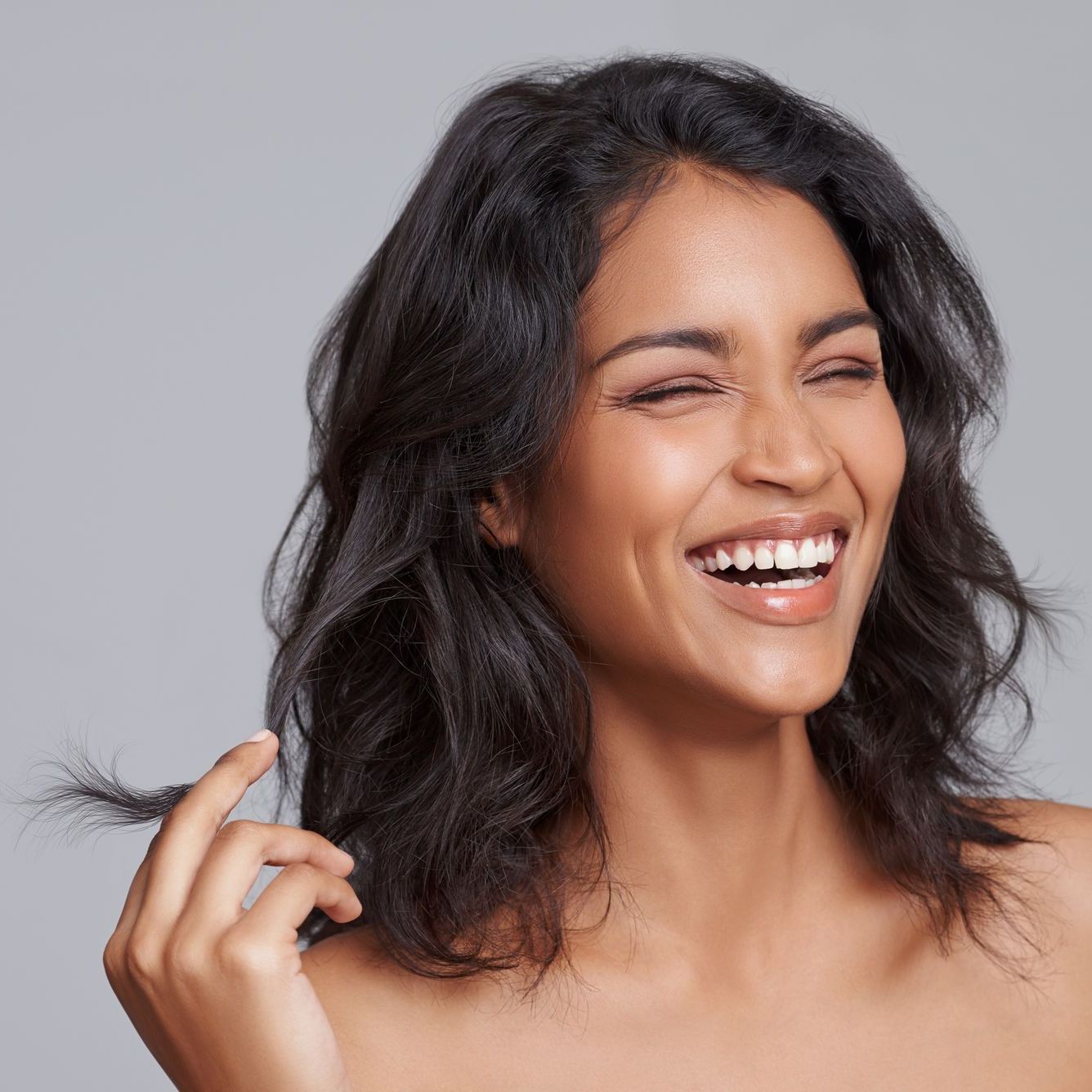 a woman with her eyes closed is smiling and holding her hair at ERA Wellness Spa