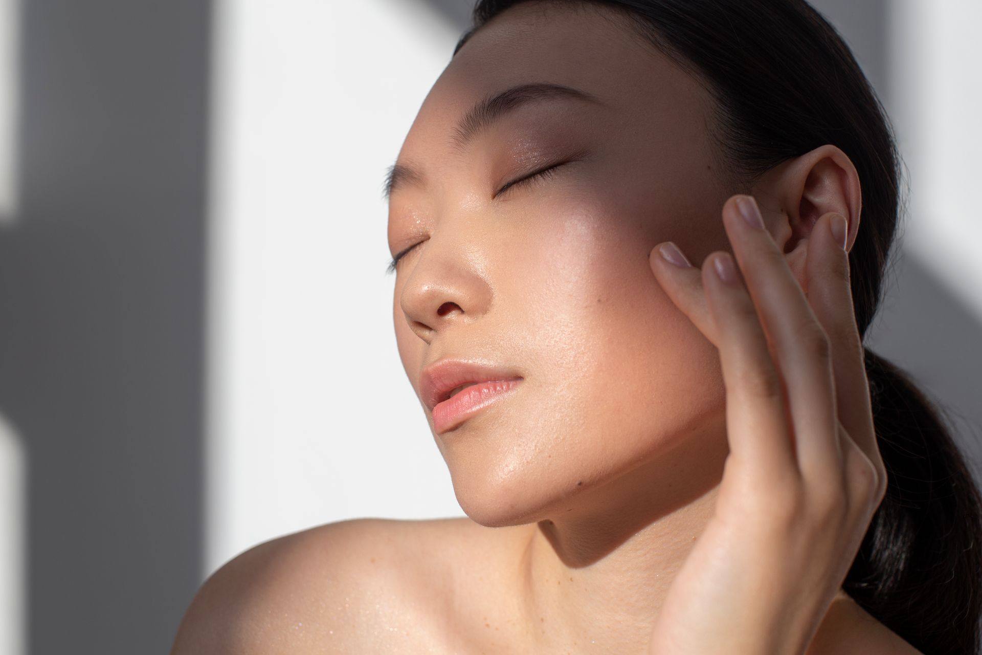 a woman with her eyes closed touches her face with her hand at ERA Wellness Spa