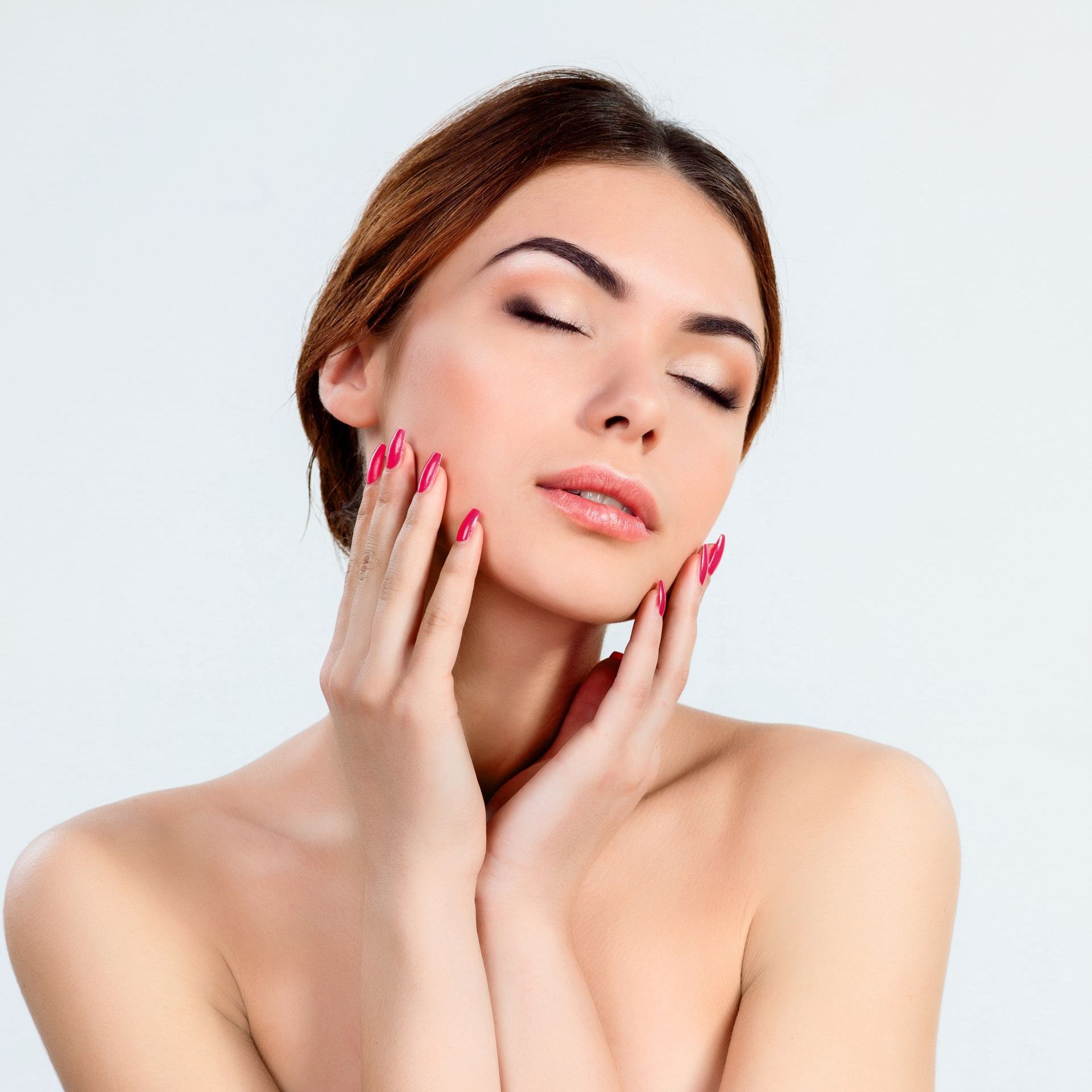 Woman with pink nails touches her face at ERA Wellness Spa