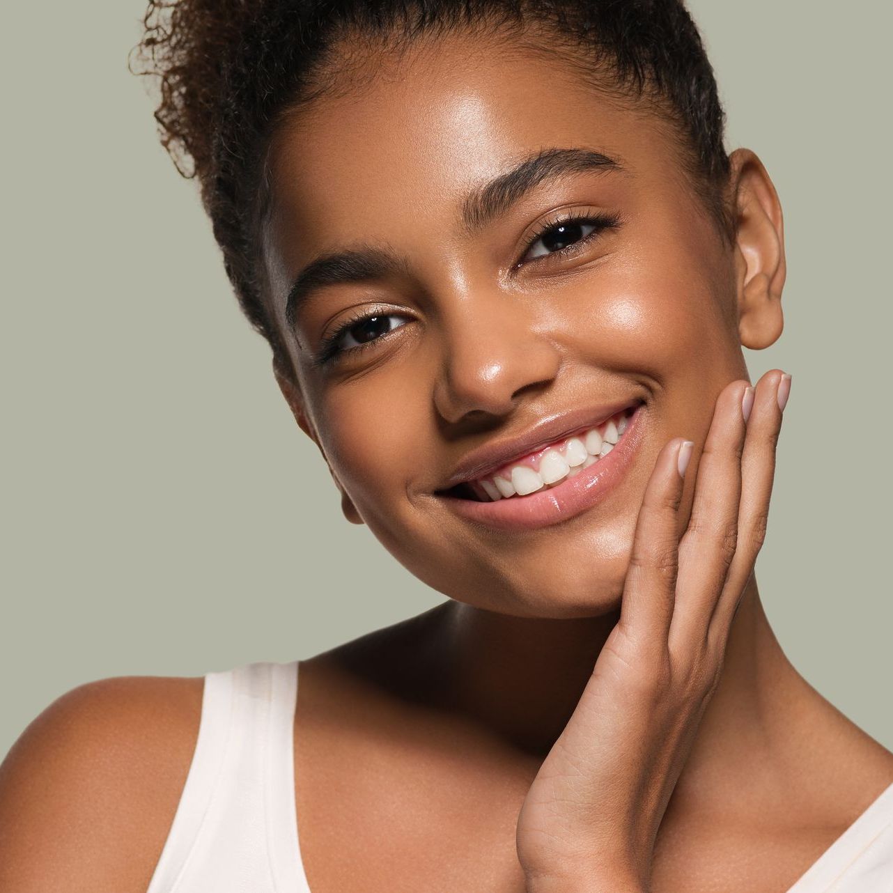a woman is smiling and touching her face with her hand at ERA Wellness Spa in Georgetown, KY