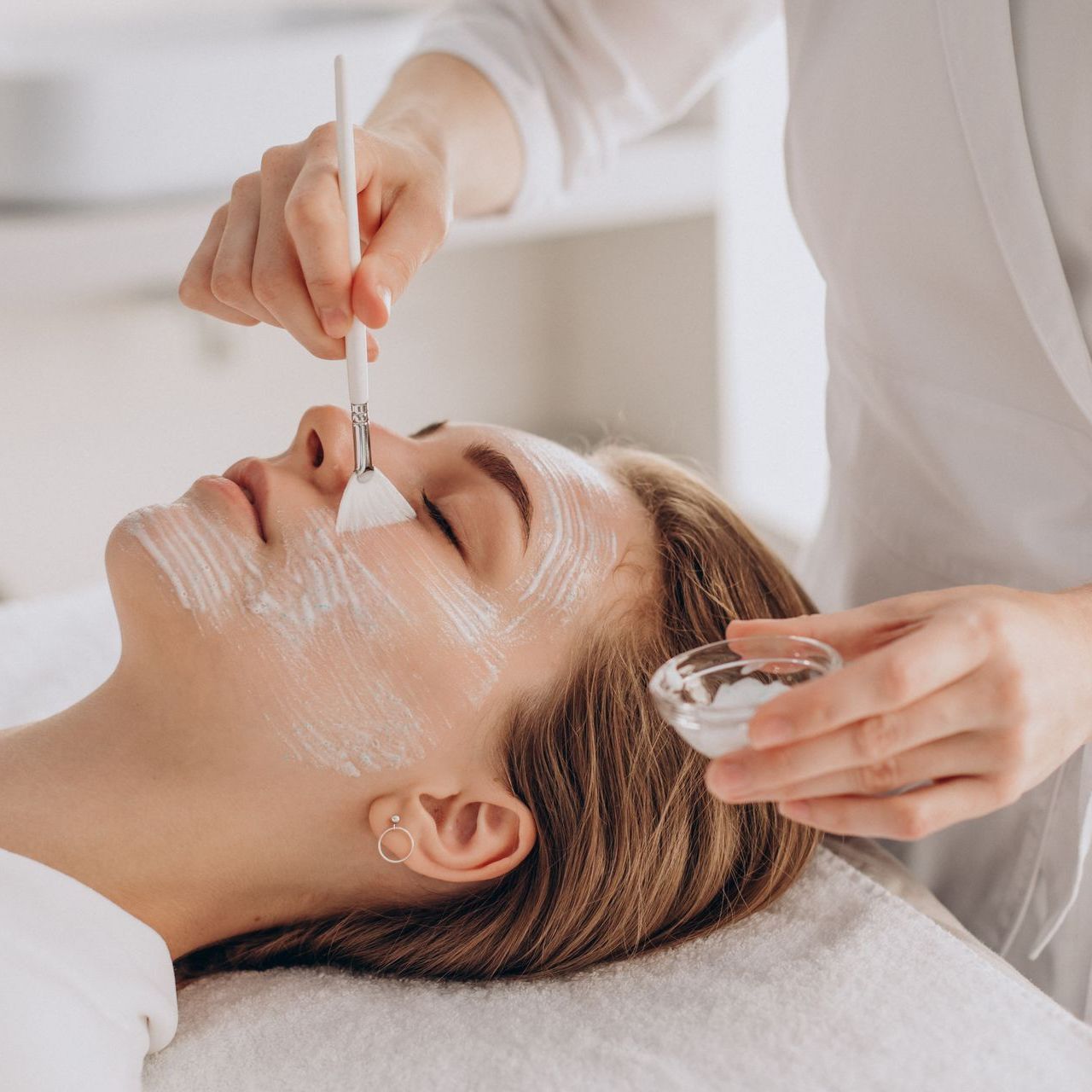 a woman is getting a facial treatment with a brush at ERA Wellness Spa