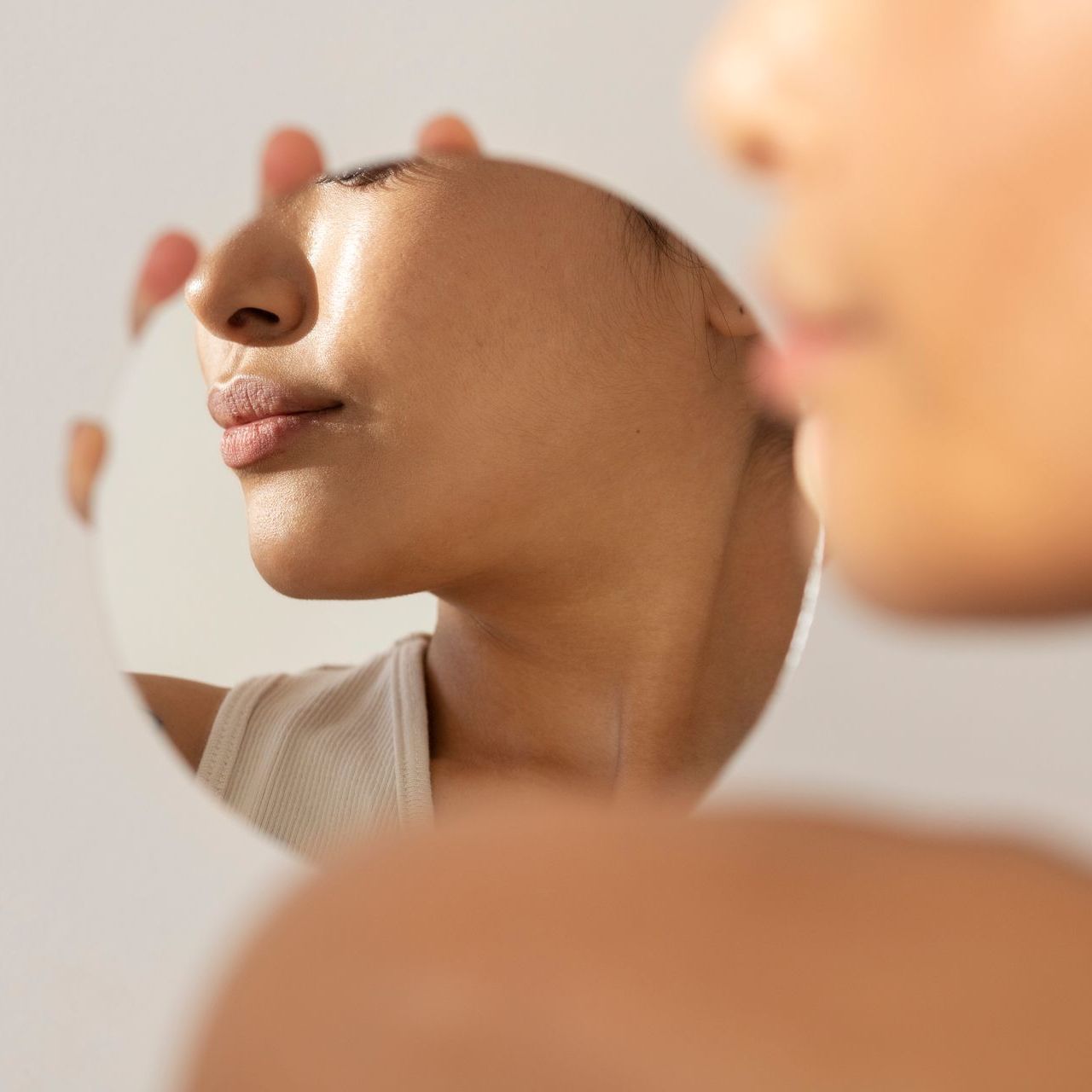 A woman is looking at her face in a mirror at ERA Wellness Spa in Georgetown, KY