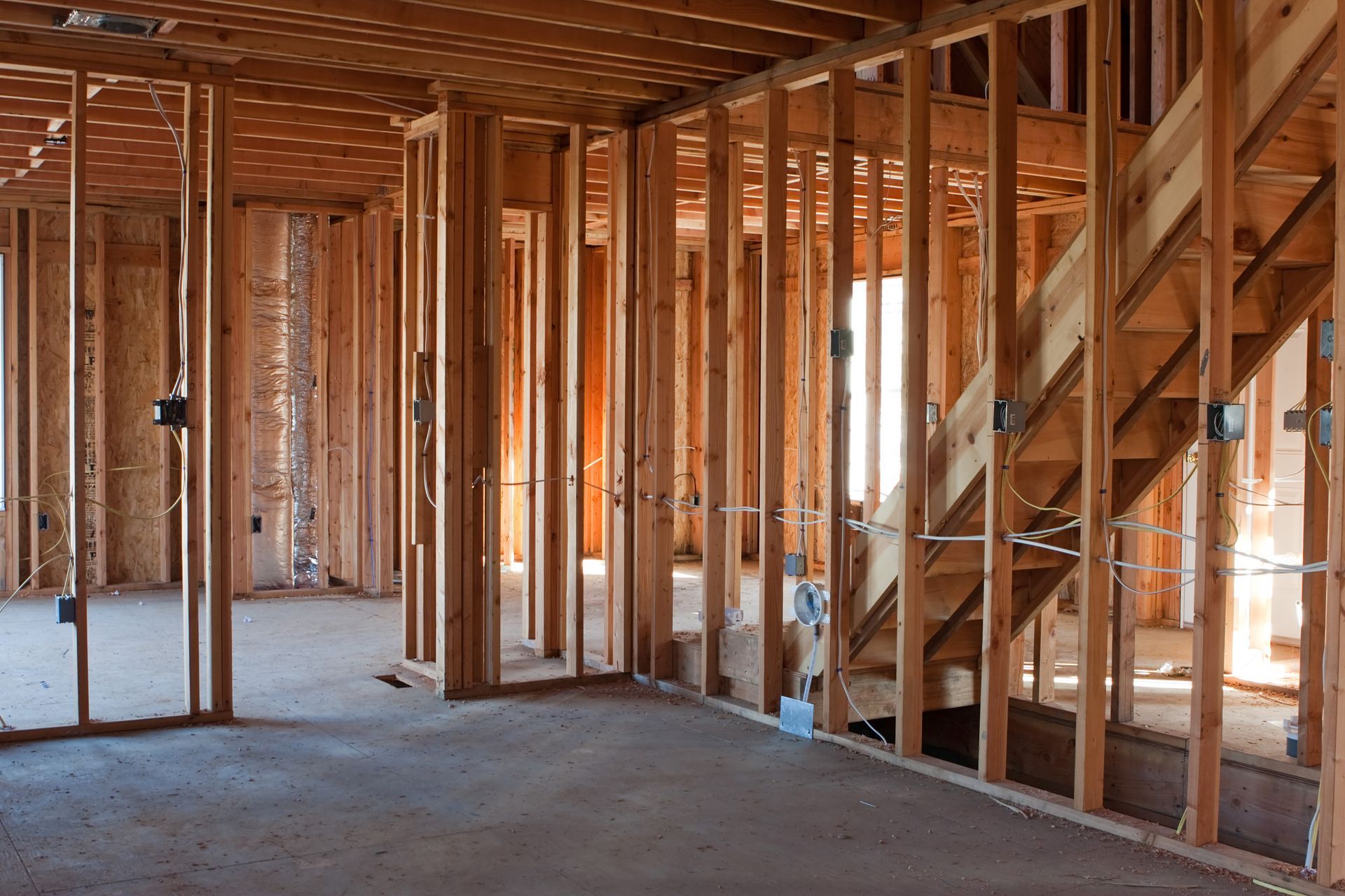 Une maison est en construction avec des poutres en bois et des escaliers.