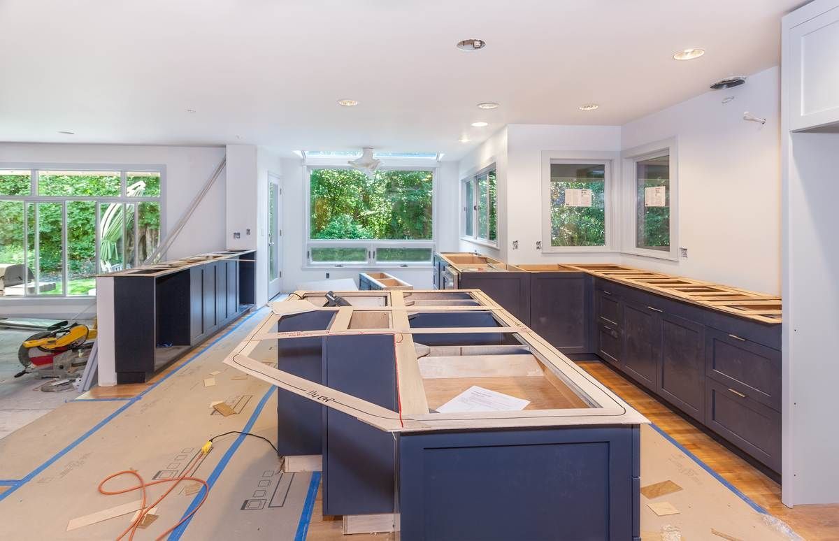 Rénovation de cuisine en cours avec armoires shaker bleu marine installées et gabarits de comptoir sur l'îlot