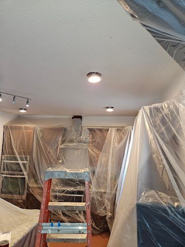 A ladder is sitting in a room covered in plastic.