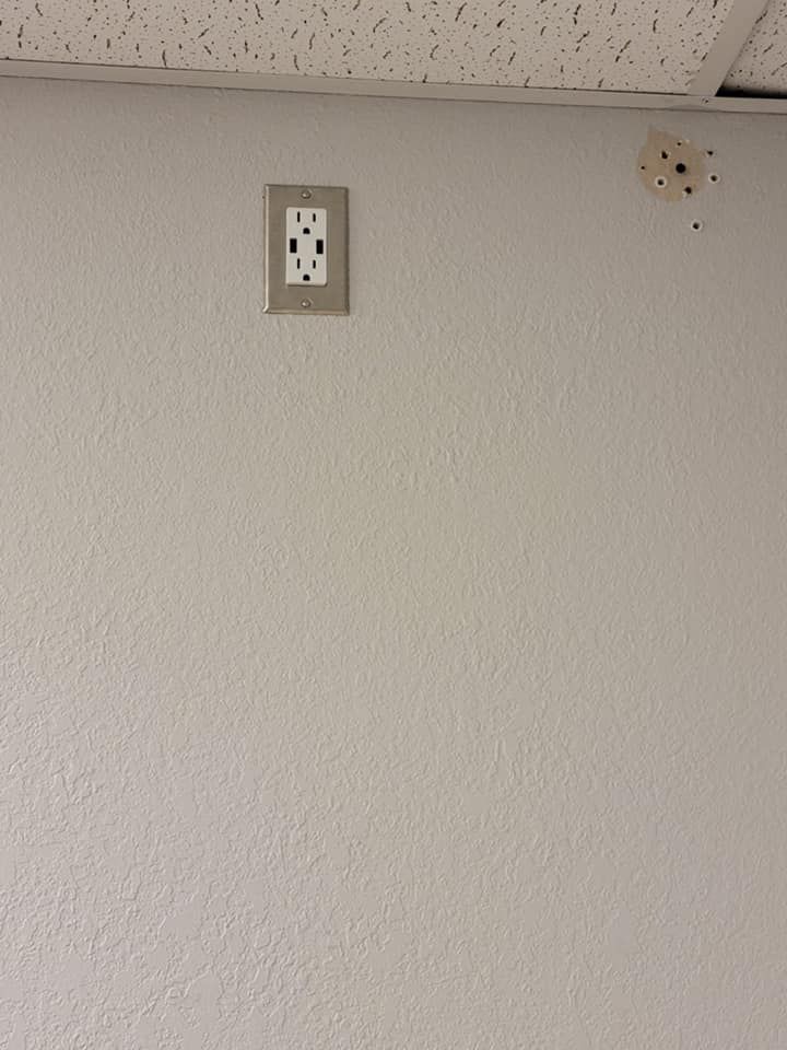 A white wall with a electrical outlet on it.