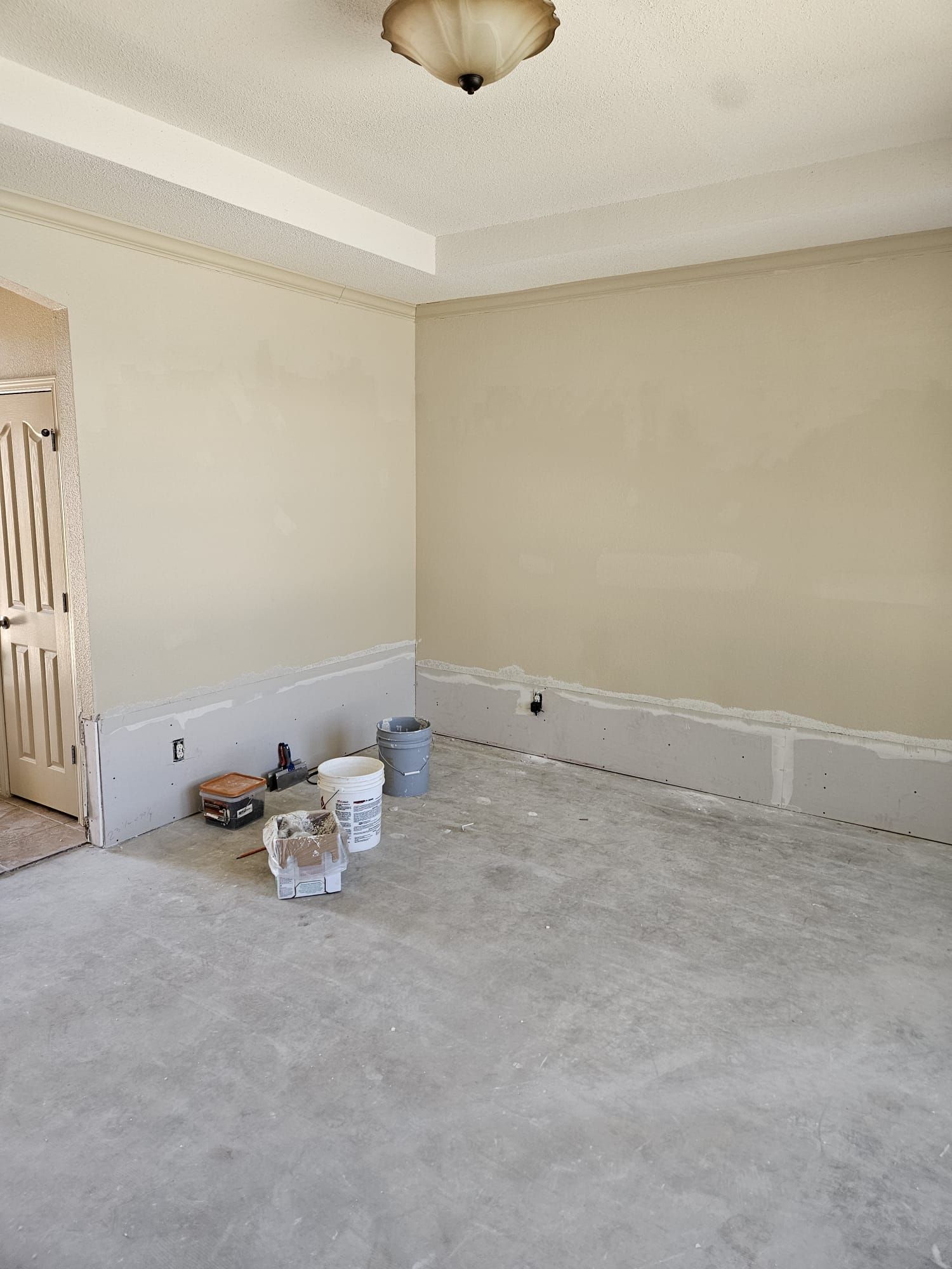 An empty room with buckets of paint on the floor.