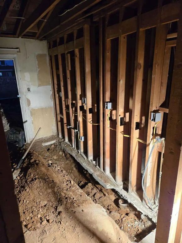 A room with a lot of wooden beams and a lot of dirt on the floor.