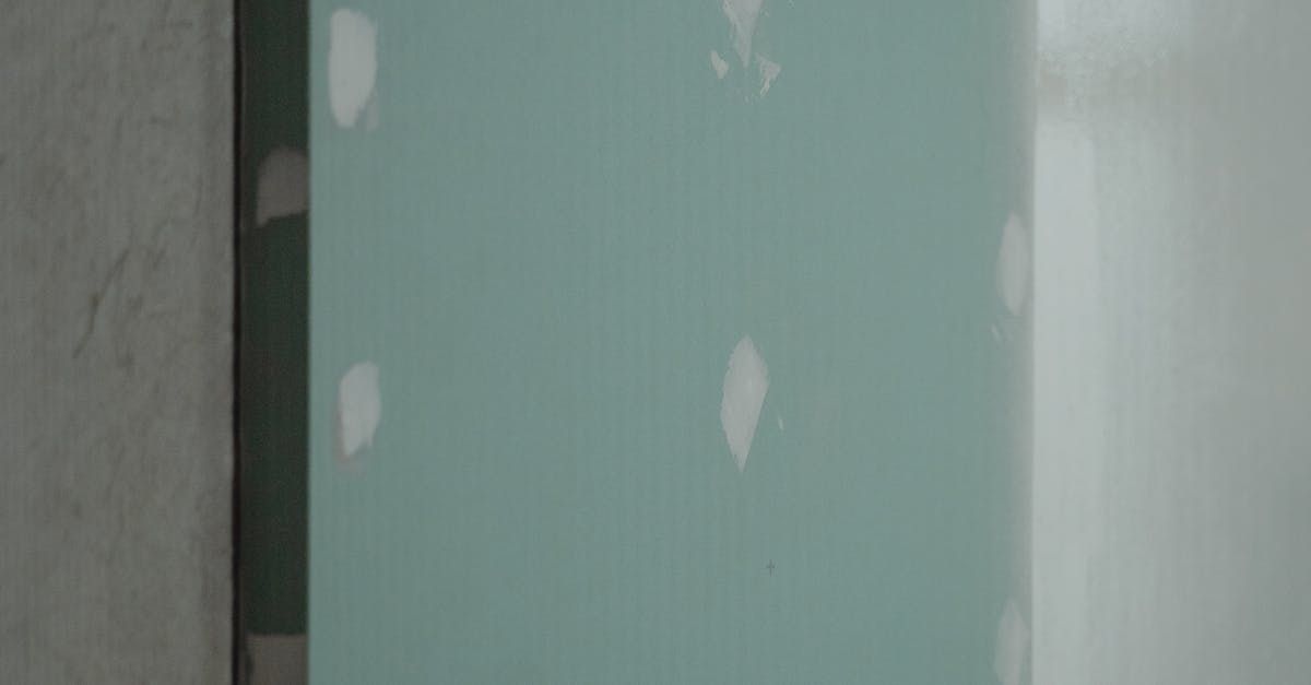 Partially painted wall with light green panel and white patches beside a gray surface