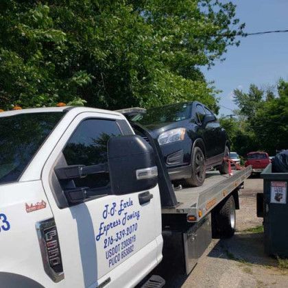 A black car being towed on a flatbed tow truck.