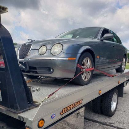 Blue Jaguar car secured on a tow truck.