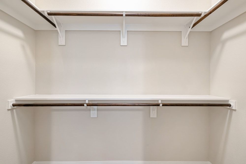 An empty walk-in closet with a shelf and clothes racks at Marquis at The Woodlands in Spring, TX.