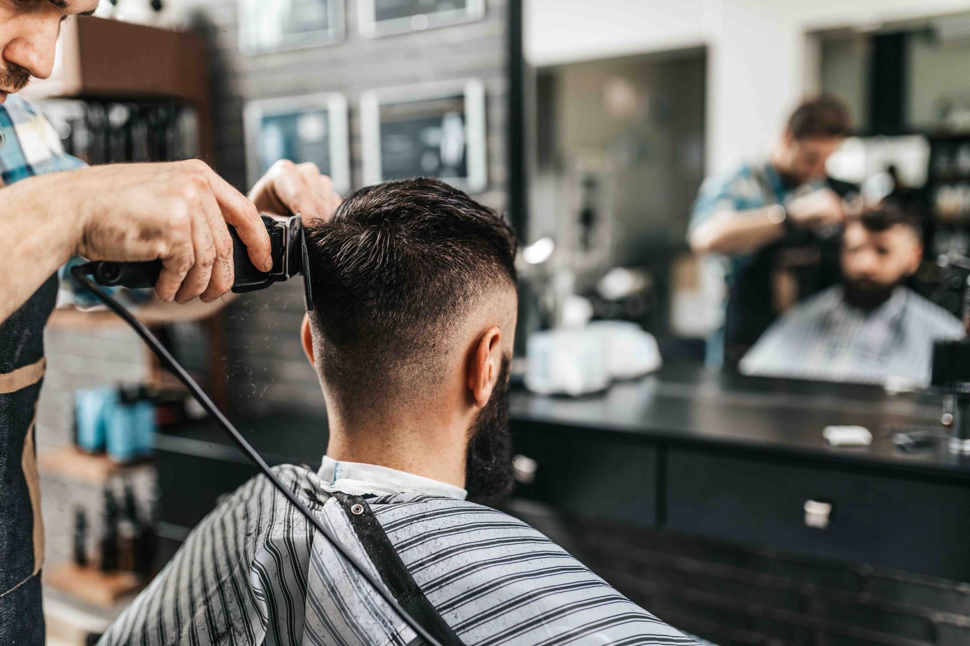 A man is getting his hair cut by a barber in a barber shop.