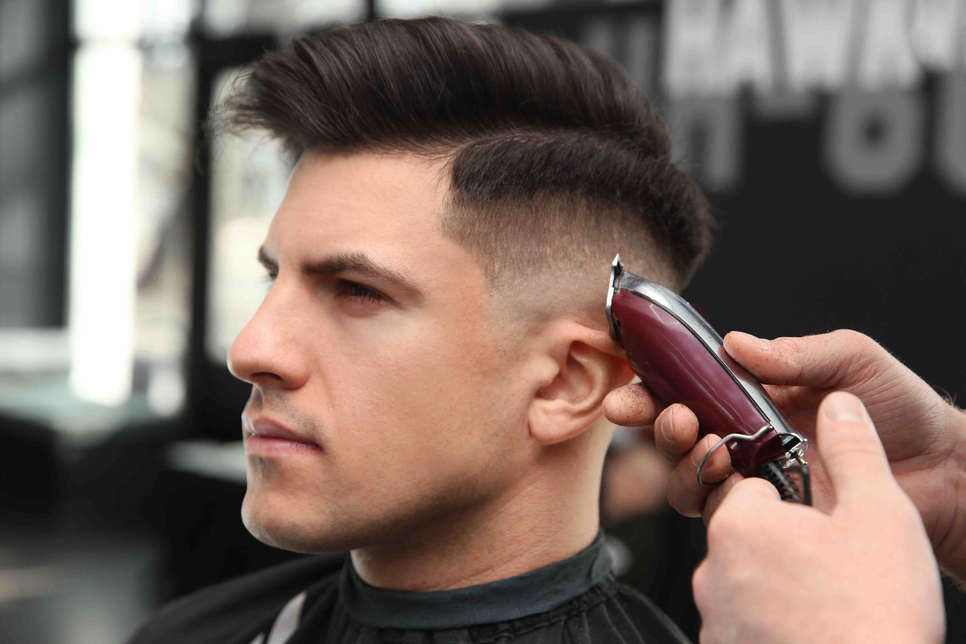 A man is getting his hair cut by a barber in a barber shop.
